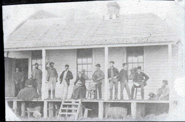 Image of people sitting and standing on front porch of cable house, Whites Bay.